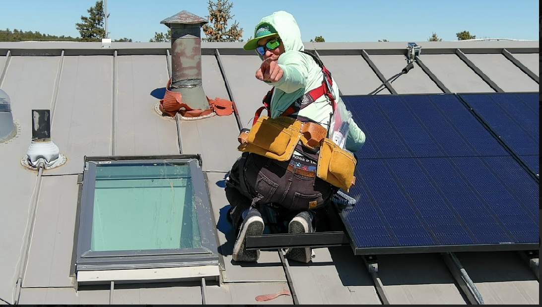 man installs solar panel on a roof